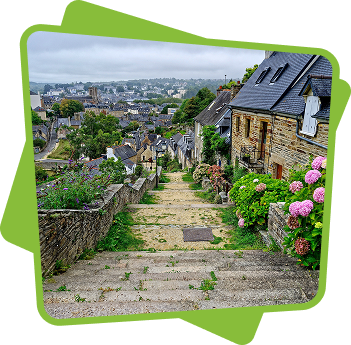 Escalier de pierre menant à un village breton avec maisons en ardoise et hortensias