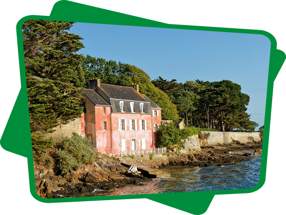 Maison rose aux volets blancs sur une côte rocheuse bretonne en bord de mer